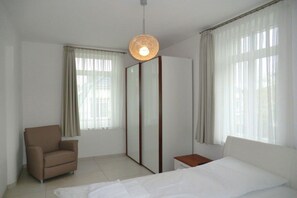 Une chambre d’hôtel avec un lit, une chaise, une armoire et une table de chevet.