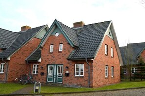 A row of brick houses with pitched roofs and a bicycle parked in front. - Green Eilun - House Section 5 (Wyk auf Föhr)