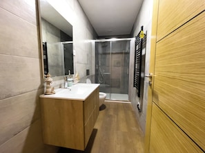 A modern bathroom with a wooden vanity, a glass shower enclosure, and a toilet. - House Sleeps 4 With Parking and Balcony (Tarouca)