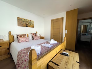 A hotel room with a bed, bedside tables, a painting, a wardrobe, and a bathroom visible through an open door. - House Sleeps 4 With Parking and Balcony (Tarouca)