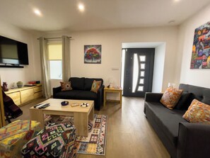 A living room with a sofa, a coffee table, a TV, and a door leading to another room. - House Sleeps 4 With Parking and Balcony (Tarouca)