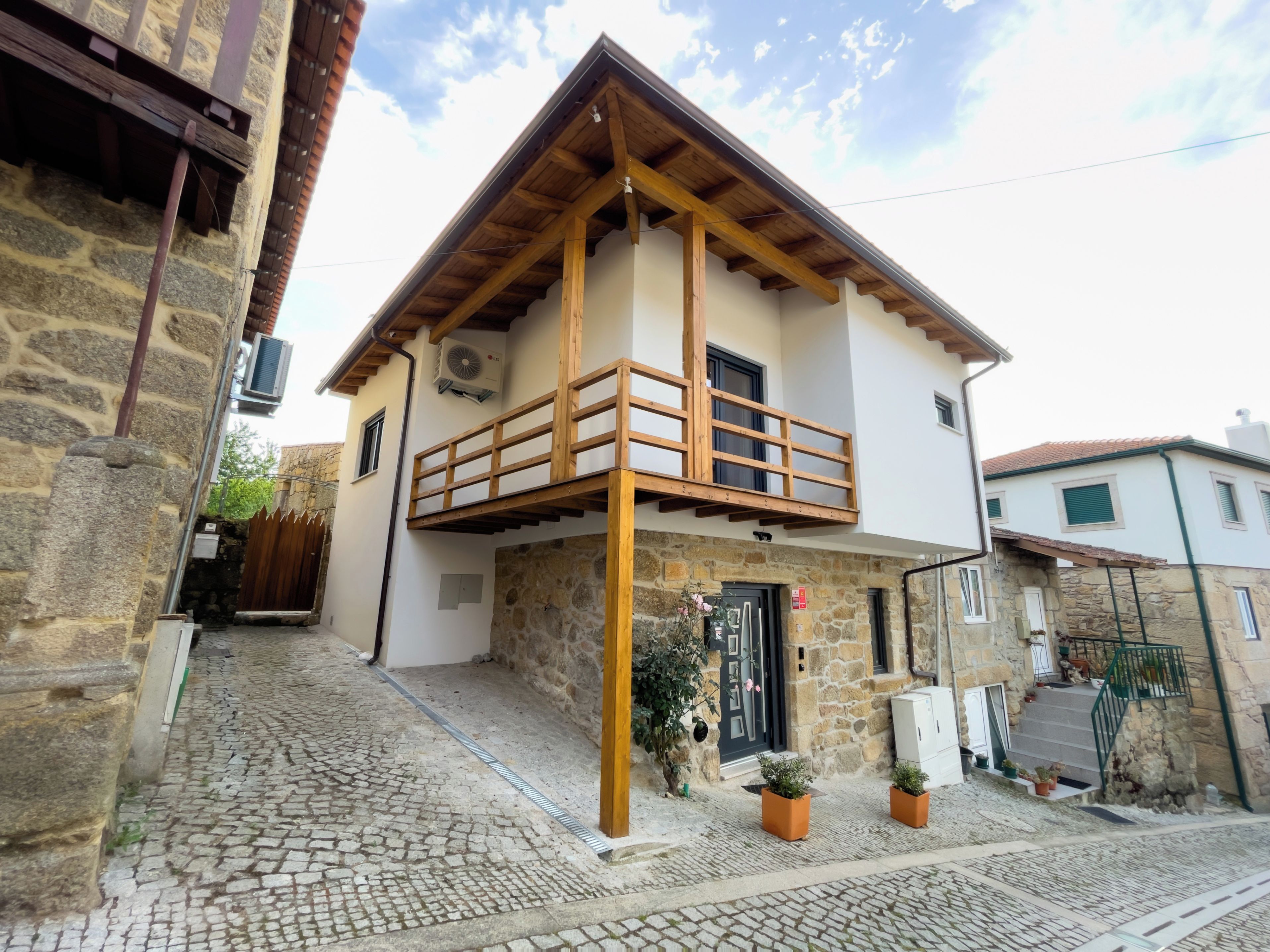 A two-story building with a stone facade, wooden balcony, and a cobblestone street.