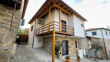 A two-story building with a stone facade, wooden balcony, and a cobblestone street.