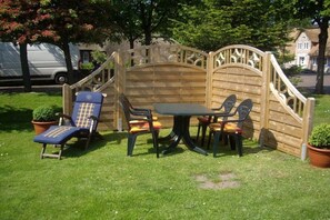 An outdoor seating area with a wooden fence, a table, and four chairs. - Holiday apartment in Föhr with 1 bedroom (Nieblum)