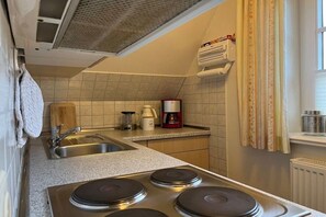 A compact kitchen with a sink, stove, and coffee maker. - Holiday apartment in Föhr with 1 bedroom (Nieblum)