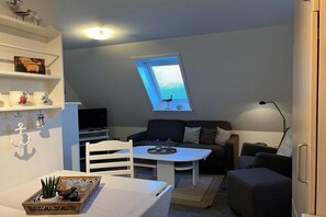Um espaço de estar compacto com mesa de jantar, sofá, TV e claraboia.