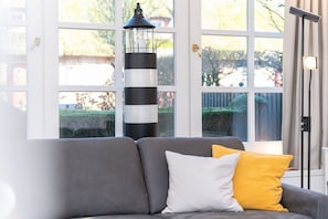 A room with a grey sofa, a black and white striped lamp, and a view through large windows. - Reethus WE 3, Blue mussel (Borgsum)