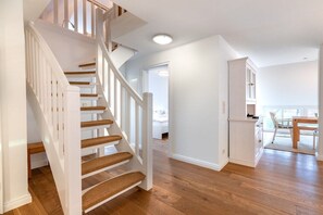 Eine Treppe mit Holzdielen und weißen Geländern, die zu einer Empfangsebene im zweiten Stock führt.