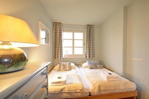 A room with two beds, a lamp, a window with curtains, and a framed picture on the wall. - Holiday apartment in Föhr with 1 bedroom (Nieblum)