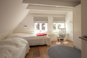 A bedroom with two beds, a window with blinds, a chair, and a small table. - Holiday home in Oldsum with swimming pool (Oldsum)