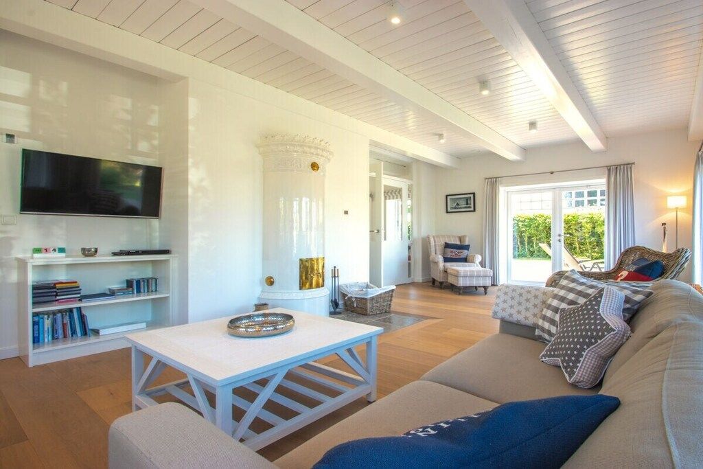 A modern living room with a white sofa, a coffee table, a bookshelf, and a television.