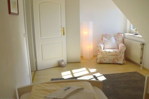 Une chambre à coucher avec un lit, une chaise, un radiateur et une fenêtre.