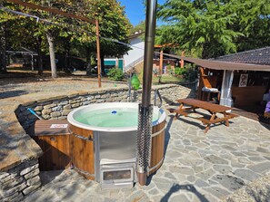 A hot tub with a wooden deck and stone walls, a picnic table, and a stone pathway. - New Listing (Piemonte)