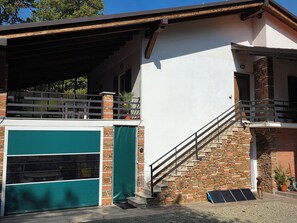Un edificio de dos pisos con garaje, escalera y balcón.