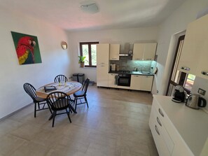 A compact kitchen with a dining area, a single window, and a parrot painting on the wall. - New Listing (Piemonte)