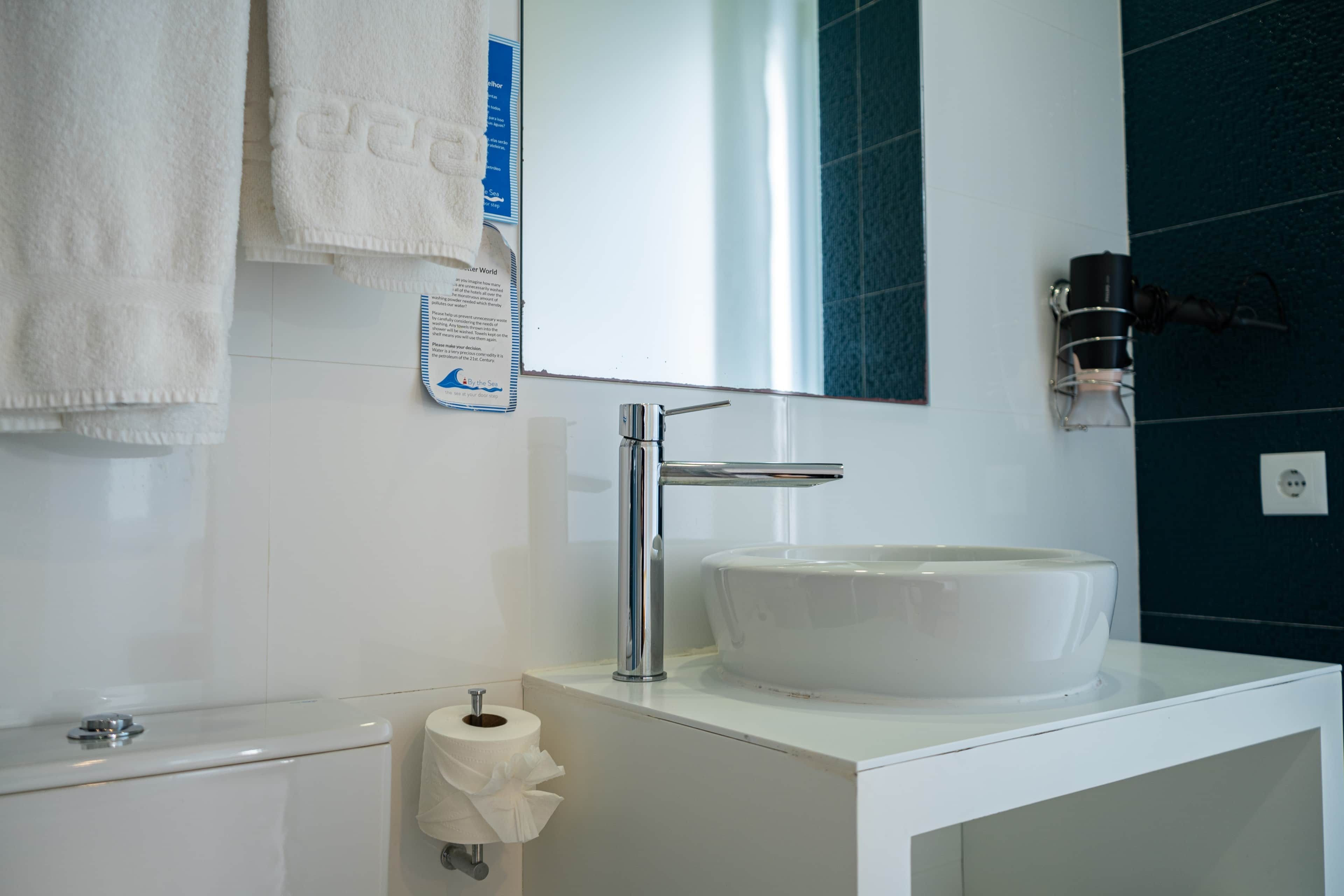 Ein modernes Badezimmer mit einem weißen Waschbecken, einem Spiegel und einem Handtuchhalter.