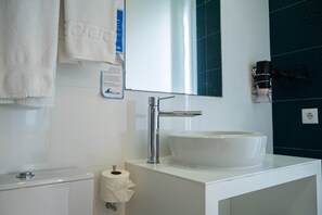 A modern bathroom with a white sink, a mirror, and a towel rack. - Deluxe Double Suite with Balcony and Sea View (Nazaré)