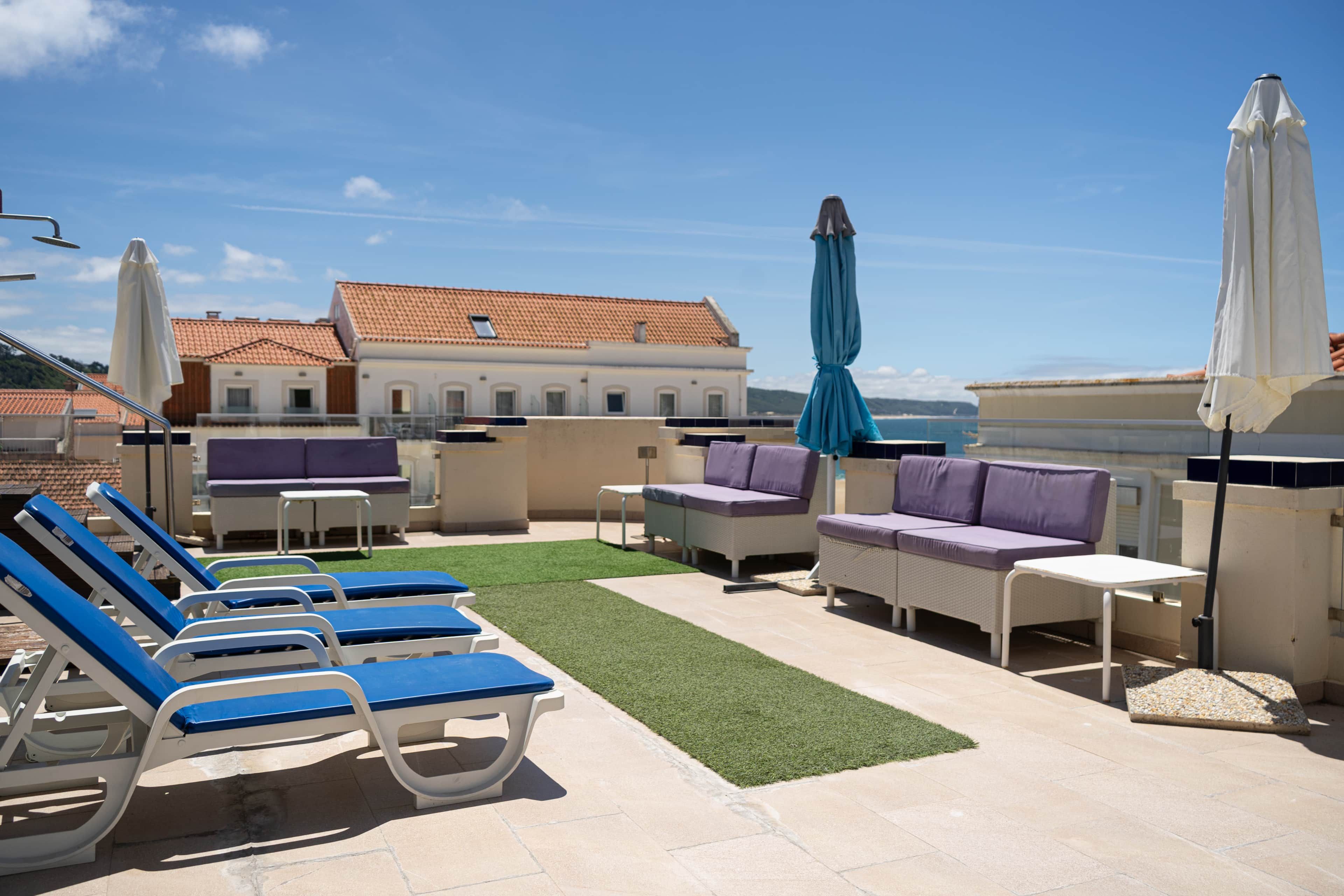 Een terras op het dak met lounge stoelen, een klein tafeltje en parasols.