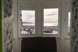 Una habitación con vista a una playa y un estacionamiento, a través de dos ventanas.