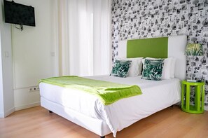 A bedroom with a bed, a green headboard, white bedding, a green throw blanket, and a wall with a collage of black and white photos. - Deluxe Double Suite with Balcony and Sea View (Nazaré)