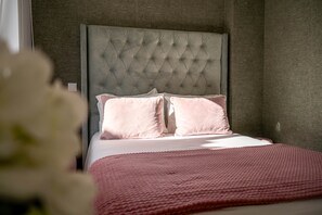 A bedroom with a tufted headboard, two pillows, and a pink blanket. - Double Junior Suite Street View (Nazaré)