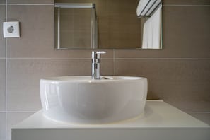 A bathroom with a white sink, a mirror, and a towel rack.