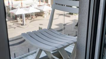 Een witte stoel op een balkon met uitzicht op gebouwen en een heldere lucht.
