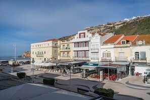 A coastal town with buildings, outdoor seating, and a view of the sea. - Double Room Square and Sea View (Nazaré)