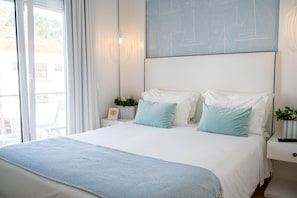 A bedroom with a large bed, a nightstand, a wall-mounted light, and a window with curtains.