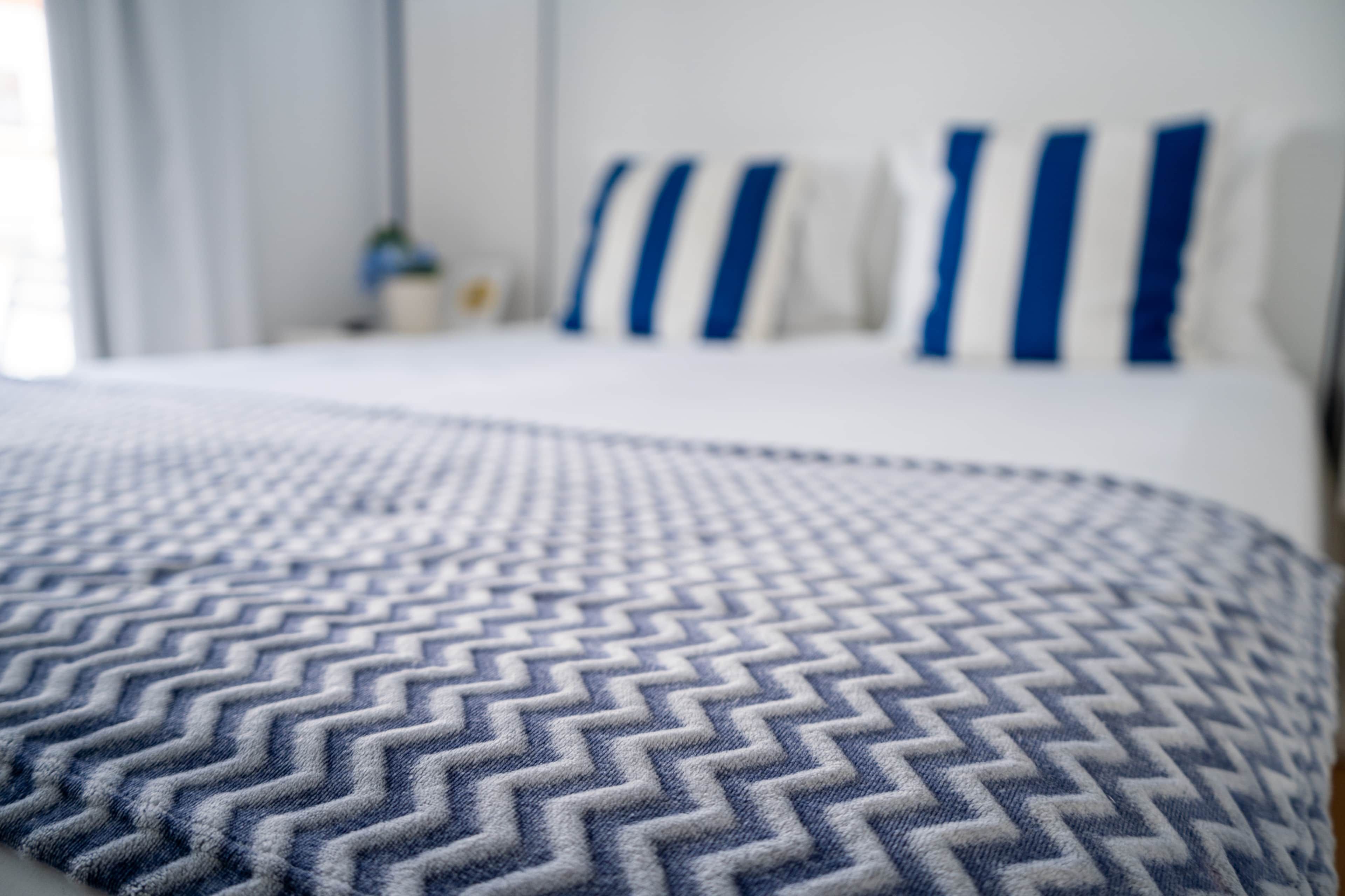 Una cama con una colcha estampada y almohadas con rayas azules.