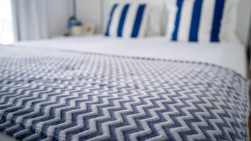 Una cama con una colcha estampada y almohadas con rayas azules.