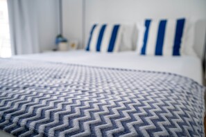 Una cama con una colcha estampada y almohadas con rayas azules.