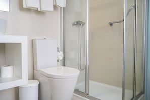 A modern bathroom with a toilet, a shower, and a glass-enclosed shower area. - Double Room Street View (Nazaré)