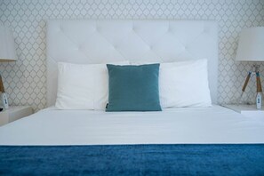 A neatly made bed with white and teal pillows, a white headboard, and a blue throw blanket. - Double Room with Balcony and Side Sea View (Nazaré)