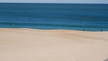 A beach with a clear sky, calm sea, and a sandy shore.