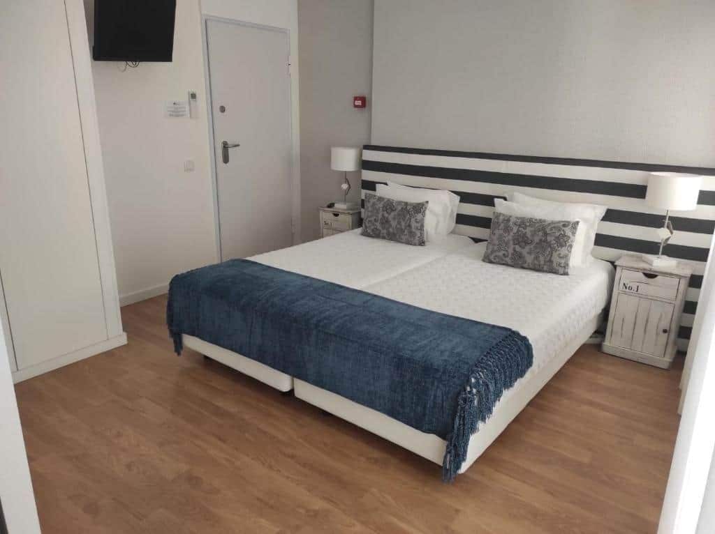 A bedroom with a bed, bedside tables, a TV, and a door.