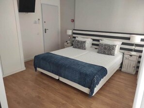 Une chambre à coucher avec un lit, des tables de chevet, un téléviseur et une porte.
