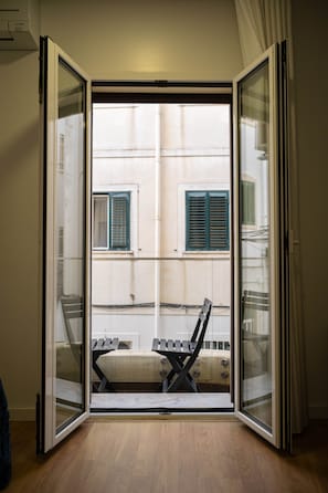 Une pièce dotée d’une porte-fenêtre coulissante donnant sur un espace extérieur aménagé avec une chaise et une table.