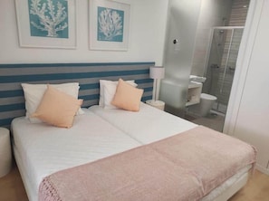 A hotel room with a bed, a bedside table, a lamp, and a shower area. - Family Suite with Balcony and Side Sea View (Nazaré)