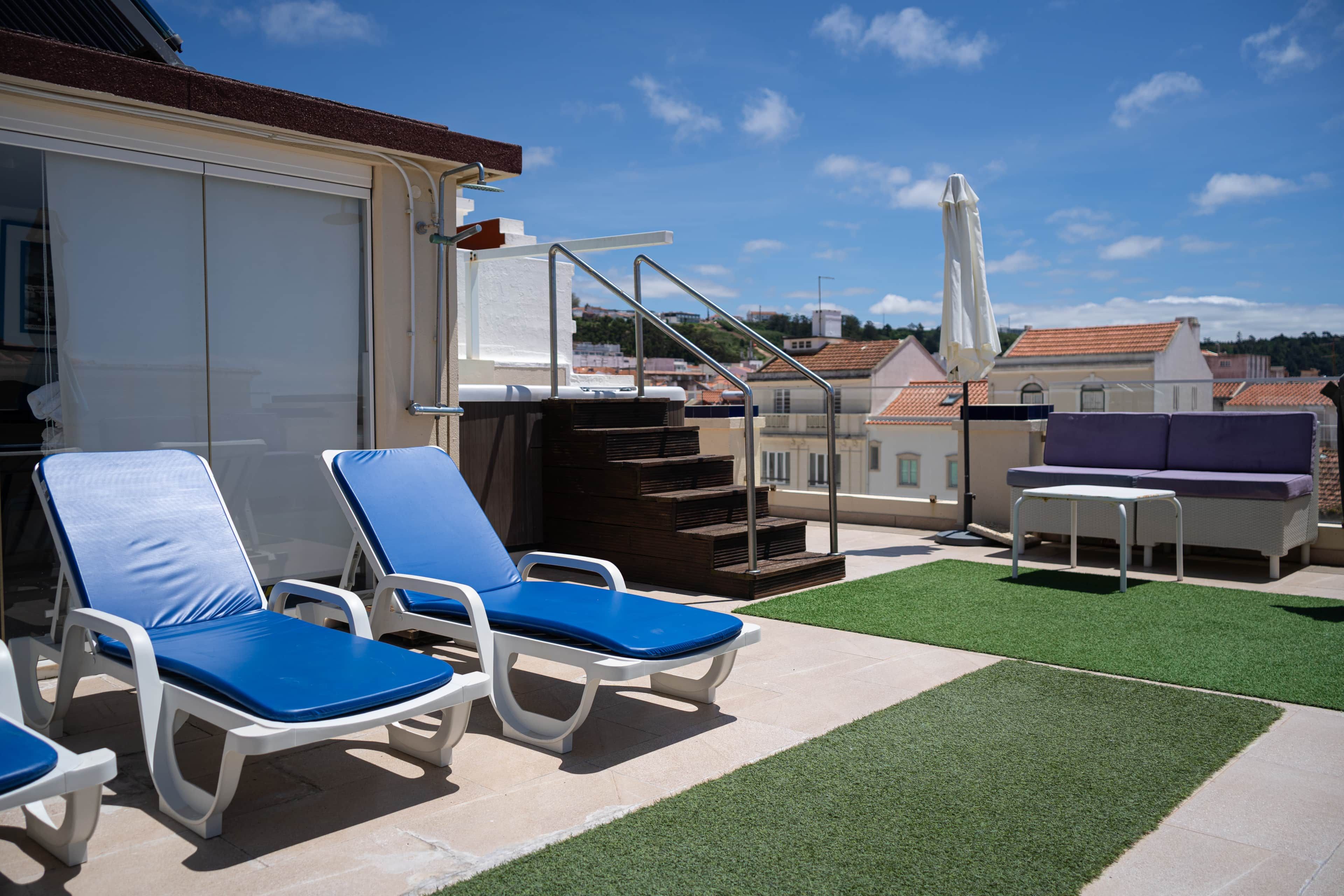 A rooftop terrace with lounge chairs, a small table, and a water feature.