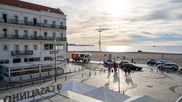 Een hotel aan de kust met uitzicht op het strand, een restaurant en een parkeerplaats met auto's.