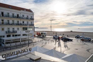 A coastal hotel with a beach view, a restaurant, and a parking area with cars.