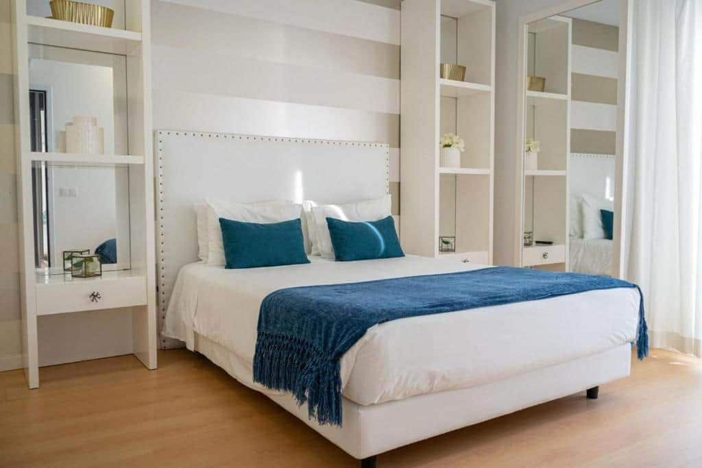 Ein Schlafzimmer mit einem großen Bett, einem Nachttisch, einem Kleiderschrank und einem Spiegel.