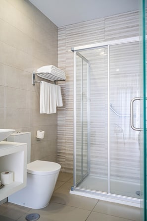 A modern bathroom with a glass-enclosed shower, a toilet, and a sink with a towel rack. - Superior Double Suite with Balcony and Sea View (Nazaré)