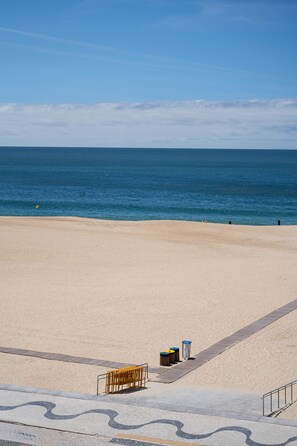 A beach with a clear sky, calm sea, and a sandy shore.