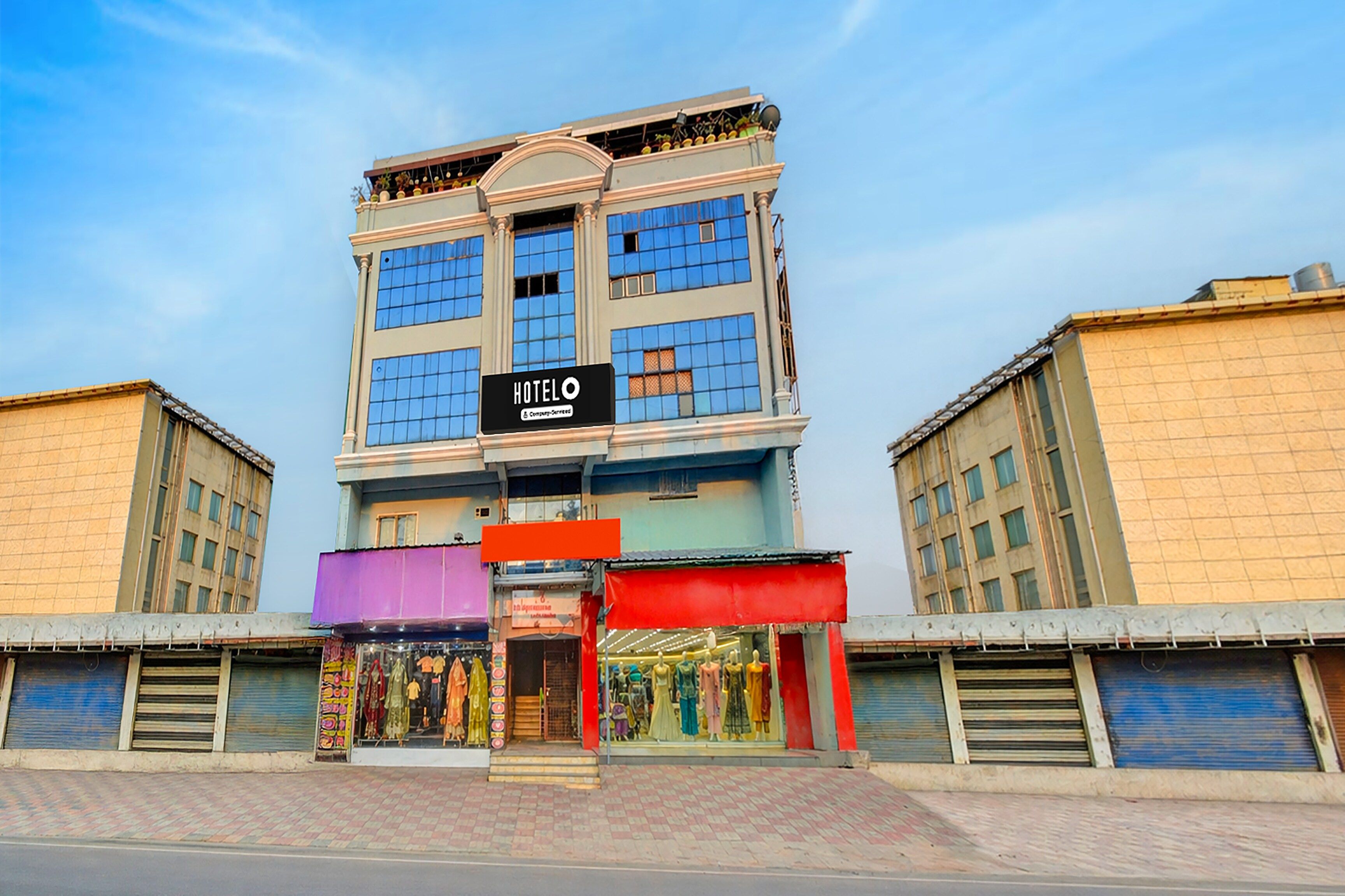Un hotel con un cartel, una tienda con maniquíes y un cielo despejado.