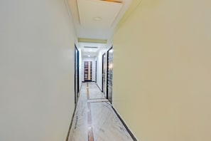 Un pasillo con suelo de mármol, puertas a ambos lados y un techo con iluminación empotrada.