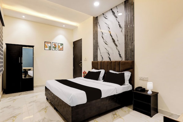 A hotel room with a large bed, a bedside table, a nightstand, a mirror, and a wall with a marble-like design.