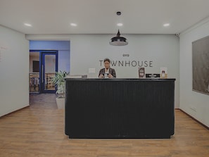 En receptionsdisk med et skilt der viser 'OYO TOWNHOUSE' og en potteplante til venstre.