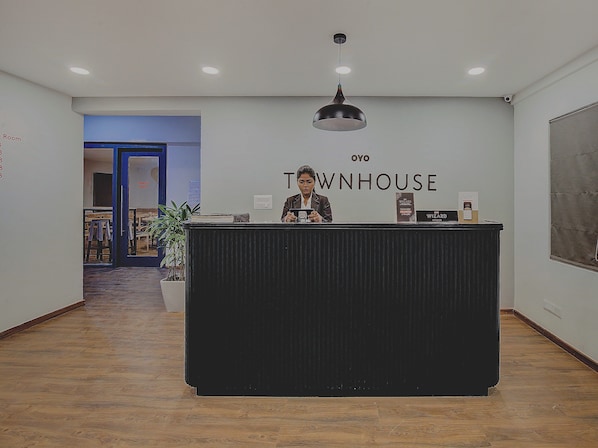 A reception desk with a sign reading 'OYO TOWNHOUSE' and a potted plant to the left. - Hotel O Evergreen (Faridabad)